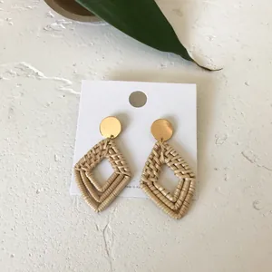 Handmade woven rattan double rhombus drop earrings with golden studs on white background