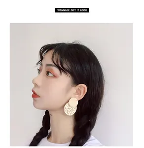 Detail of round rattan earrings with wooden studs shown on a model for a vintage look