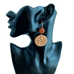 Detail of bohemian handmade straw woven drop earrings on black mannequin display stand