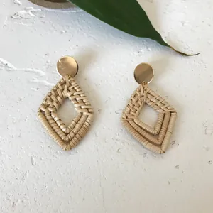 Bohemian style diamond-shaped rattan drop earrings with gold metal studs and leaf background
