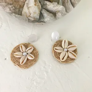 Detailed macro view of bohemian woven earrings with seashell flower and pearl center