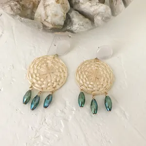 Detail of woven rattan earrings with white studs and green faceted crystal beads