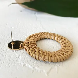 Detailed close-up of woven rattan round earrings with golden metal stud base