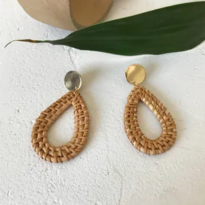 Macro detail of handmade rattan teardrop earrings with elegant golden metal studs