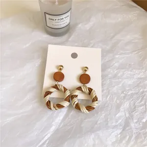 Detail of bohemian woven hoop earrings with two-tone natural wood and rattan texture