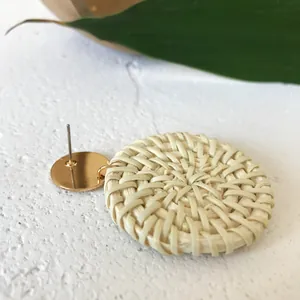 Handmade woven rattan round earrings with golden studs on a natural stone surface