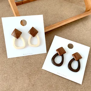 Detail of wood and resin geometric earrings in beige and coffee colors on white card
