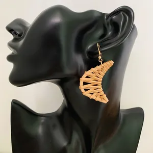 Bohemian crescent rattan drop earrings with golden hooks on black mannequin
