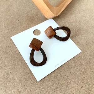 Detailed macro view of geometric wood earrings with square and teardrop contrast wood grain