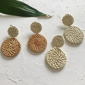 Detailweergave van handgemaakte gevlochten rotan oorbellen in crème en lichtbruin