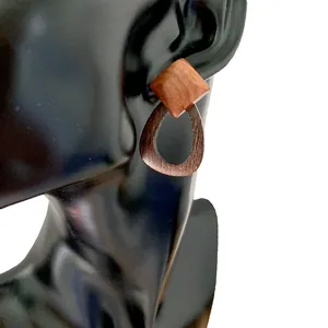 Close-up of geometric wood earrings with reddish-brown texture on black ear model