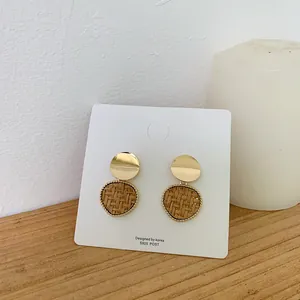 Detail of round wicker earrings with gold metal disc and S925 silver post on card