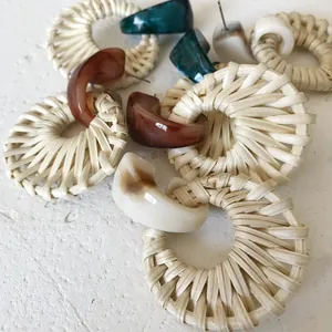 Close-up of bohemian woven rattan hoop earrings with marble resin pendants in various colors