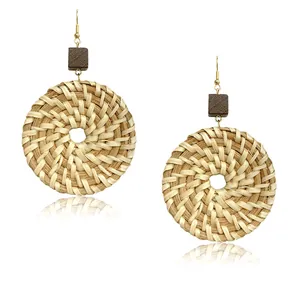 Detailed view of handmade rattan round earrings with brown wooden square studs and gold hooks