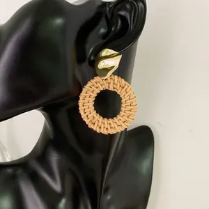 Bohemian rattan hoop earrings with gold geometric metal studs worn on a model