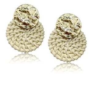 Detail of bohemian rattan earrings with hammered gold metal disc and woven texture