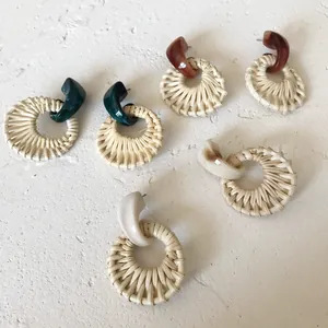 Detail showing woven rattan round earrings in dark green, brown, and cream white shades