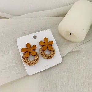 Retro floral earrings with wood petals and woven rattan hoops on white linen