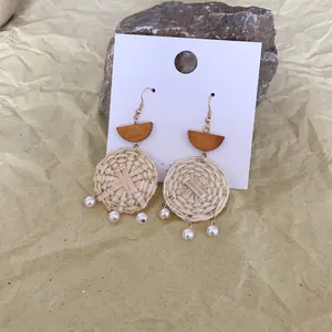 Detail of woven rattan round earrings with wooden accents and white imitation pearls
