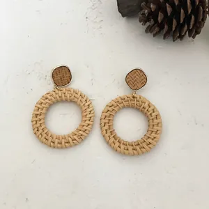 Detailaufnahme handgefertigter Rattanohrringe mit goldenen geometrischen Steckern