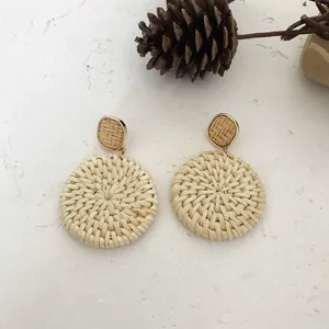 Handgefertigte Boho-Rattan-Ohrringe mit Goldmetallrahmen auf natürlichem Hintergrund