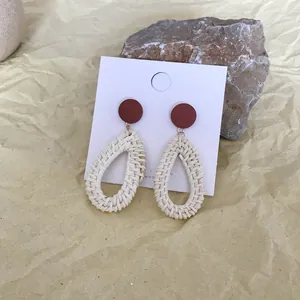 Detail of bohemian red round stud and beige woven teardrop dangle on display card