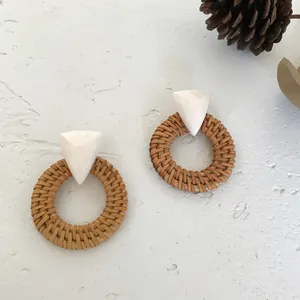 Bohemian round rattan earrings with white resin triangle details on textured background