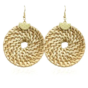 Macro shot of bohemian woven rattan hoop earrings with textured gold metallic discs