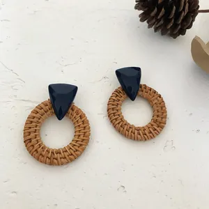 Detail of bohemian triangle resin earrings with brown rattan woven round rings