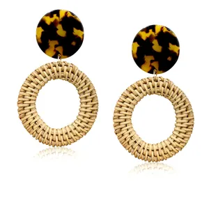 Macro view of handmade rattan weave earrings with leopard print resin top and natural texture