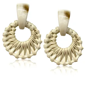 Detailed macro view of bohemian hand-woven rattan earrings with marble resin studs