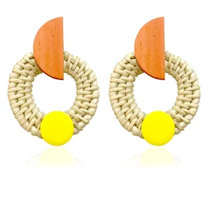 Macro shot of bohemian rattan woven earrings with colorful geometric wood accents