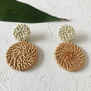 Detail van boho rotan oorbellen met een tweelaags cirkelvormig geweven stro-ontwerp