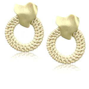 Close-up of bohemian woven rattan hoop earrings with irregular gold metal wavy studs