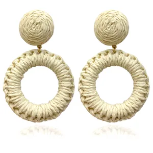 Macro detail of large cream white woven raffia hoop earrings with golden metal links