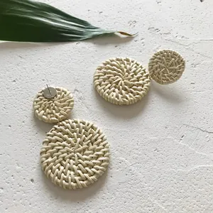 Detailopname van handgemaakte rotan oorbellen met natuurlijke strotextuur en dubbele cirkel