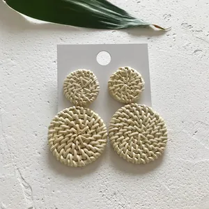 Detail van handgemaakte rotan oorbellen met dubbele cirkels van gevlochten stro op wit