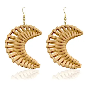 Handmade crescent rattan drop earrings with golden hooks on white reflection surface