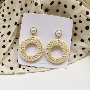 Detail of bohemian rattan drop earrings with white pearls on a stylish polka dot fabric