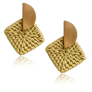 Detail of bohemian rattan and wood geometric drop earrings showing natural woven textures