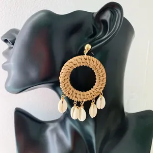 Detail of woven rattan hoop earrings with gold metal studs and natural shell pendants