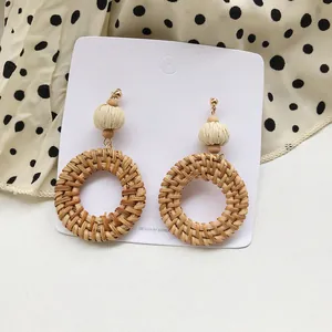 Bohemian rattan woven circle earrings with wooden beads on a stylish silk background