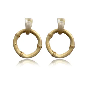Close-up of bohemian bamboo hoop earrings with beige marble texture resin stud and reflection