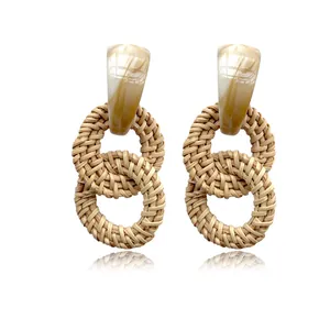 Detail of bohemian rattan earrings with marble resin studs and natural woven rings