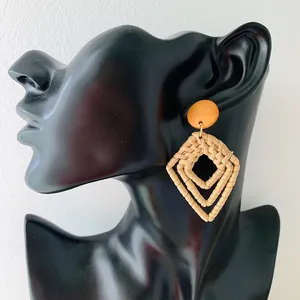 Handmade bohemian rattan earrings with geometric rhombuses shown on a black model head