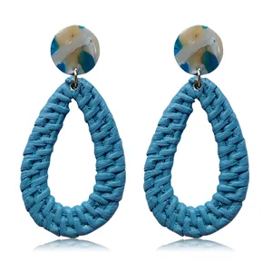 Macro detail of blue woven teardrop earrings with marble texture resin studs