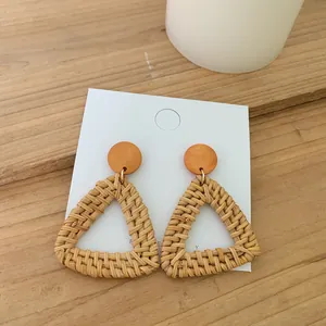 Detail of bohemian rattan triangle earrings with orange wood bead on display card