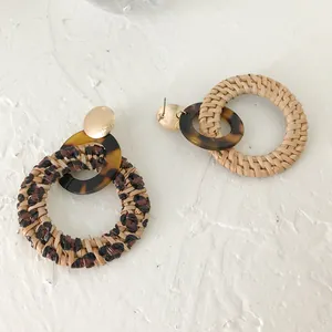 Detail van rotan oorringen met luipaardprint, goudkleurige knopjes en schildpad