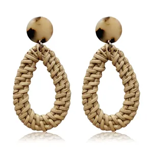 Detail view of handmade woven rattan teardrop earrings with tortoise shell resin studs