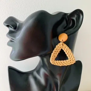 Close-up of handmade rattan diamond drop earrings on a black mannequin display